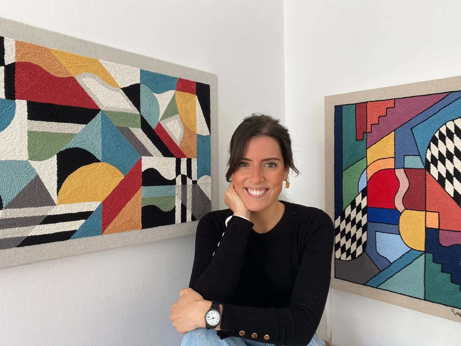 Lisbon textile artist seated between two colourful embroidered works