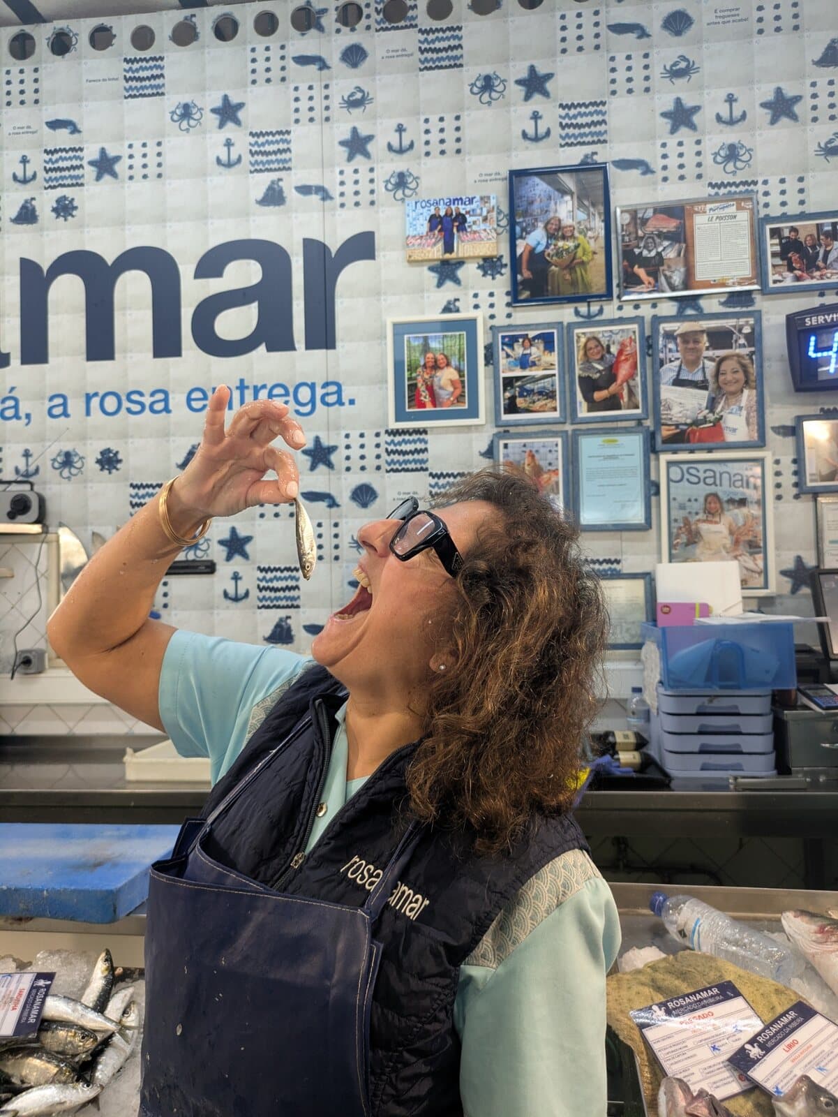 A Lisbon fishmonger playfully tasting a small fish