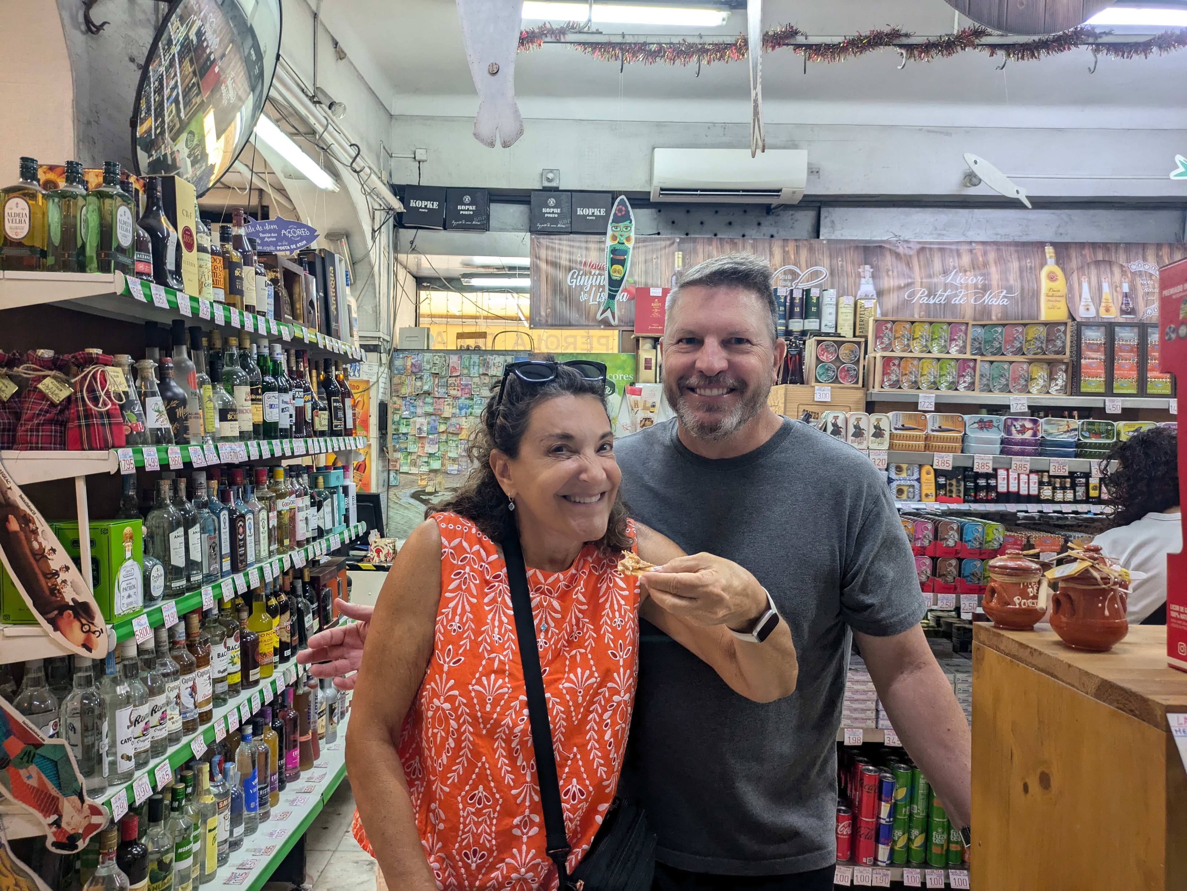 Two smiling guests sharing a moment inside a Portuguese grocery shop