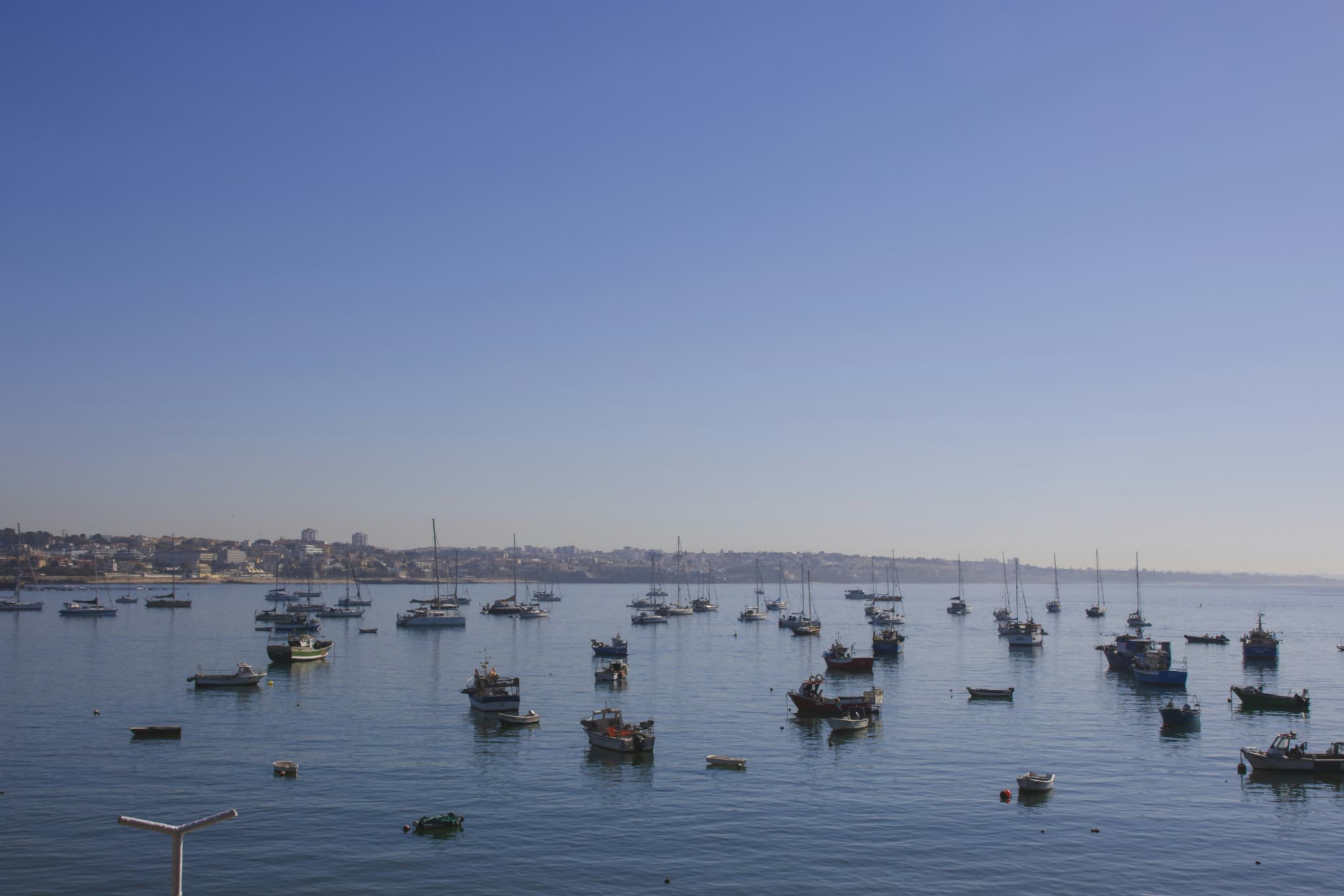 Fishing boats and yachts anchored in the calm waters of Cascais Bay