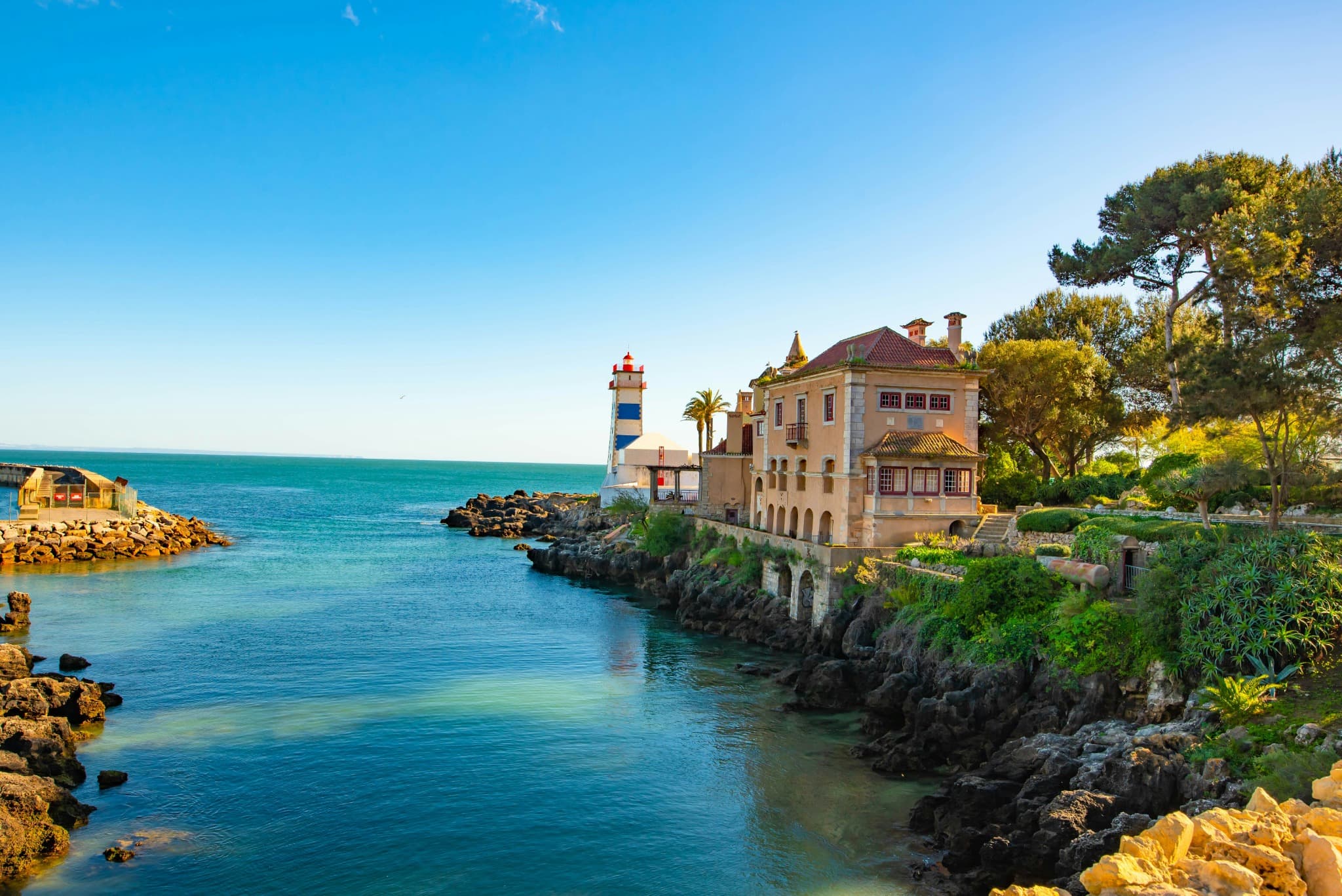 The striped Santa Marta lighthouse beside a historic seafront villa in Cascais