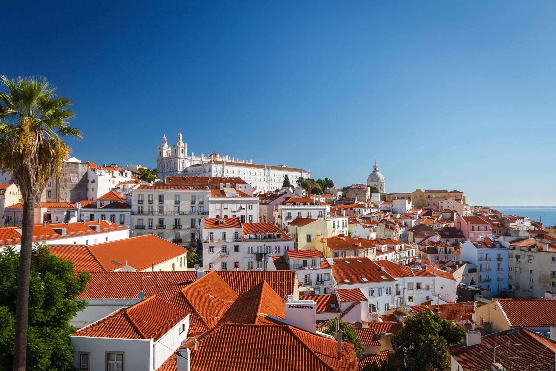 Lisbon’s red-roofed historic centre beneath a clear blue sky