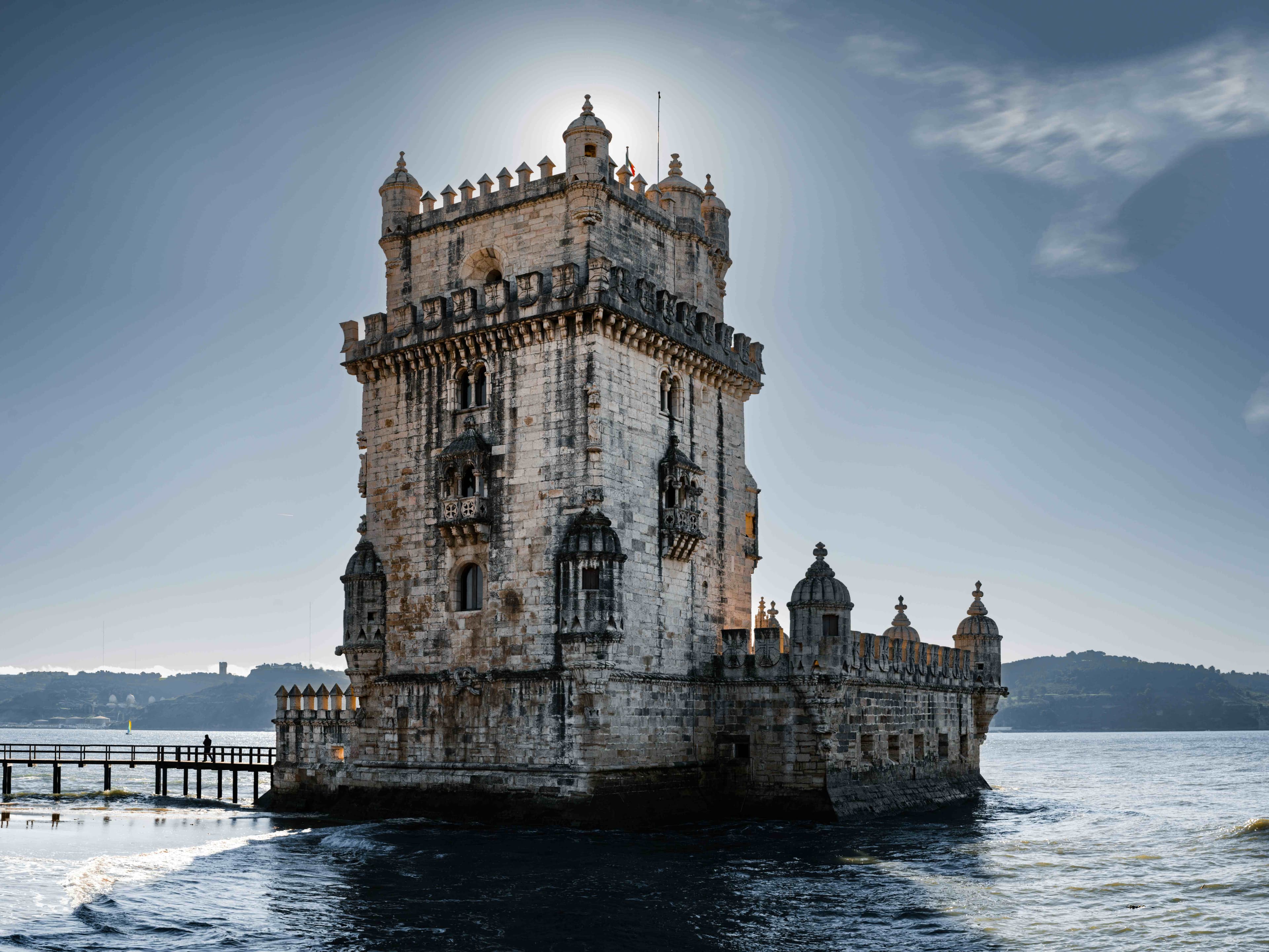 Belém Tower framed by the river and a dramatic cloudy sky