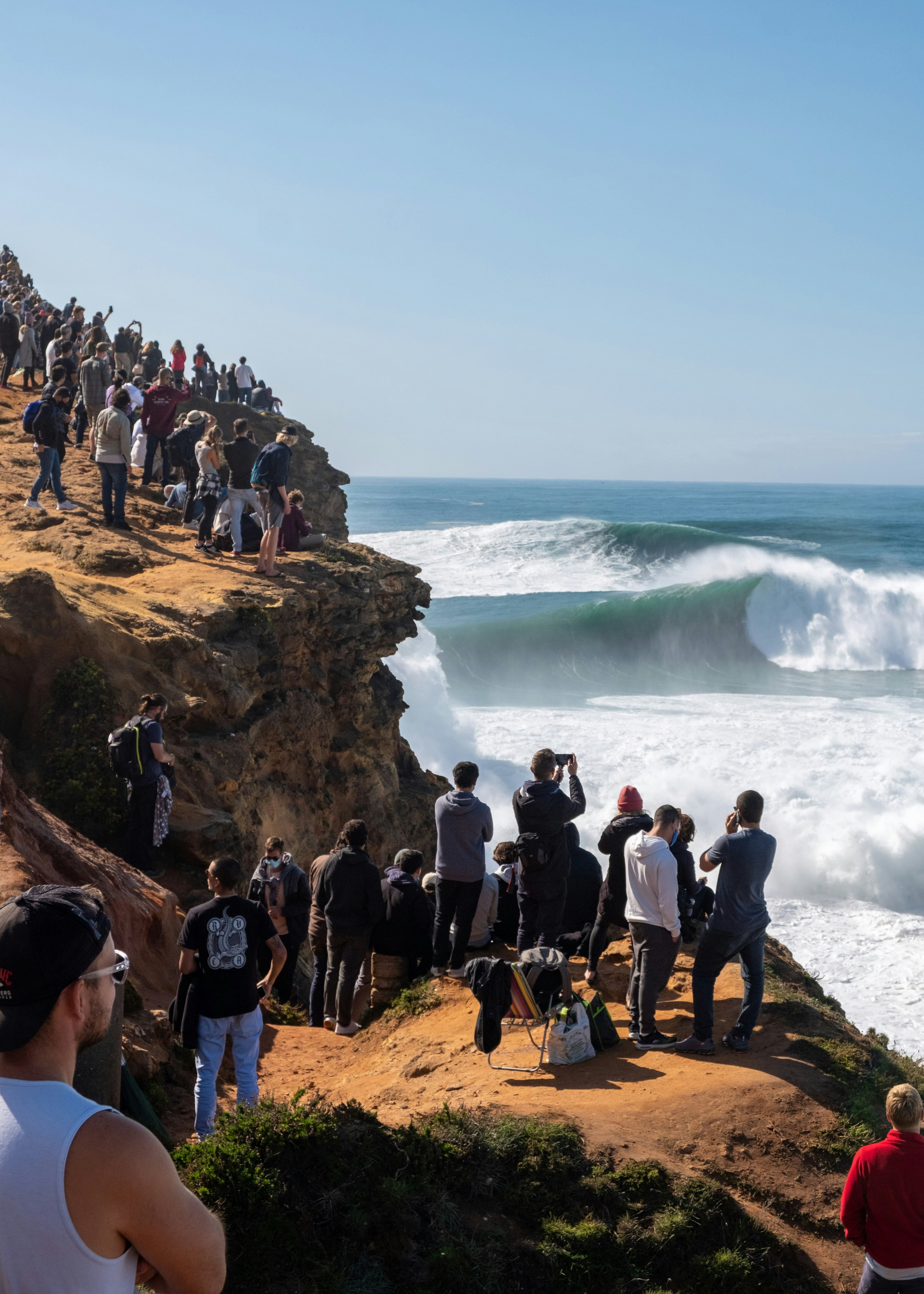 A spectator facing a large wave at Praia do Norte