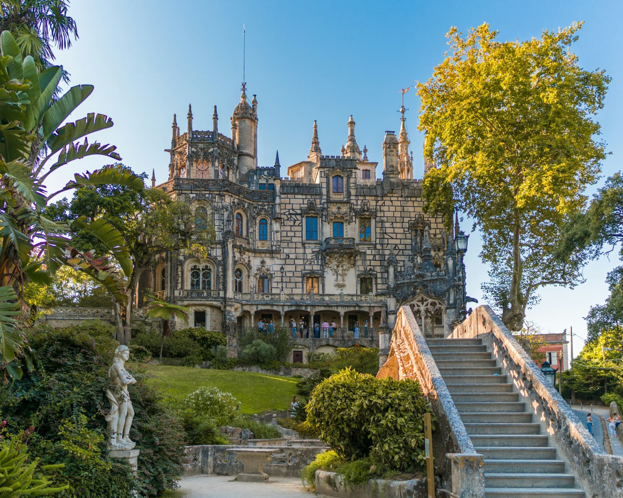 The Gothic Revival façade of Quinta da Regaleira framed by palm trees and gardens